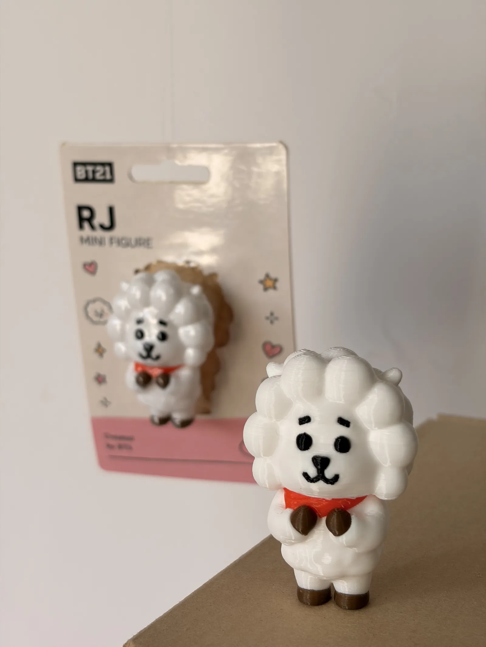 Mini figura de RJ impresa en 3D junto a su blíster