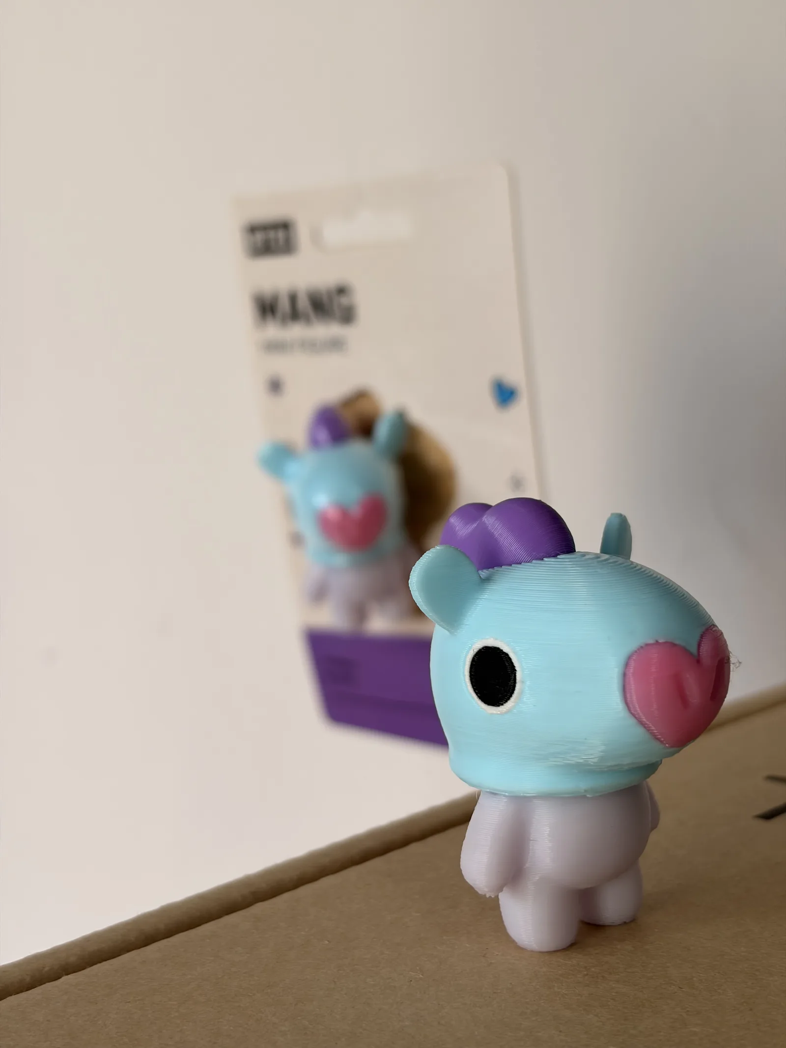 Mini figura de Mang impresa en 3D junto a su blíster