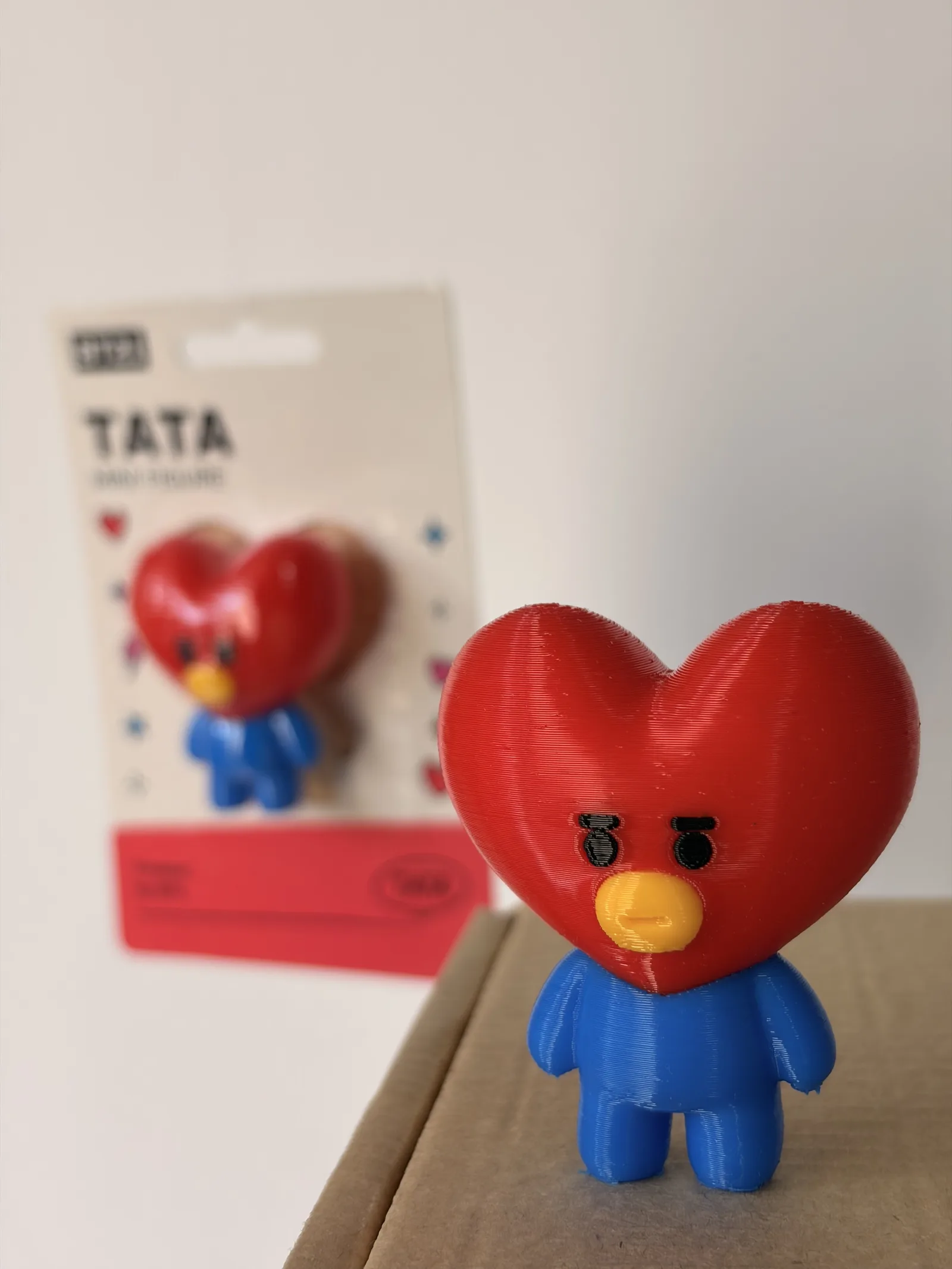 Mini figura de Tata impresa en 3D junto a su blíster