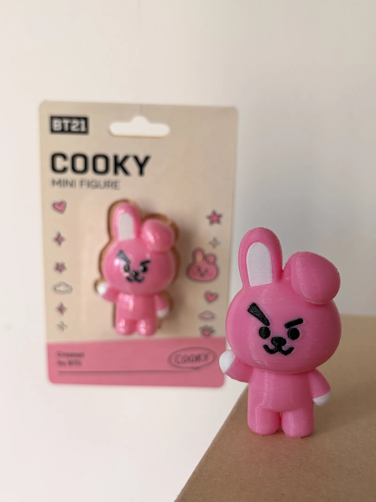 Mini figura de Cooky impresa en 3D junto a su blíster