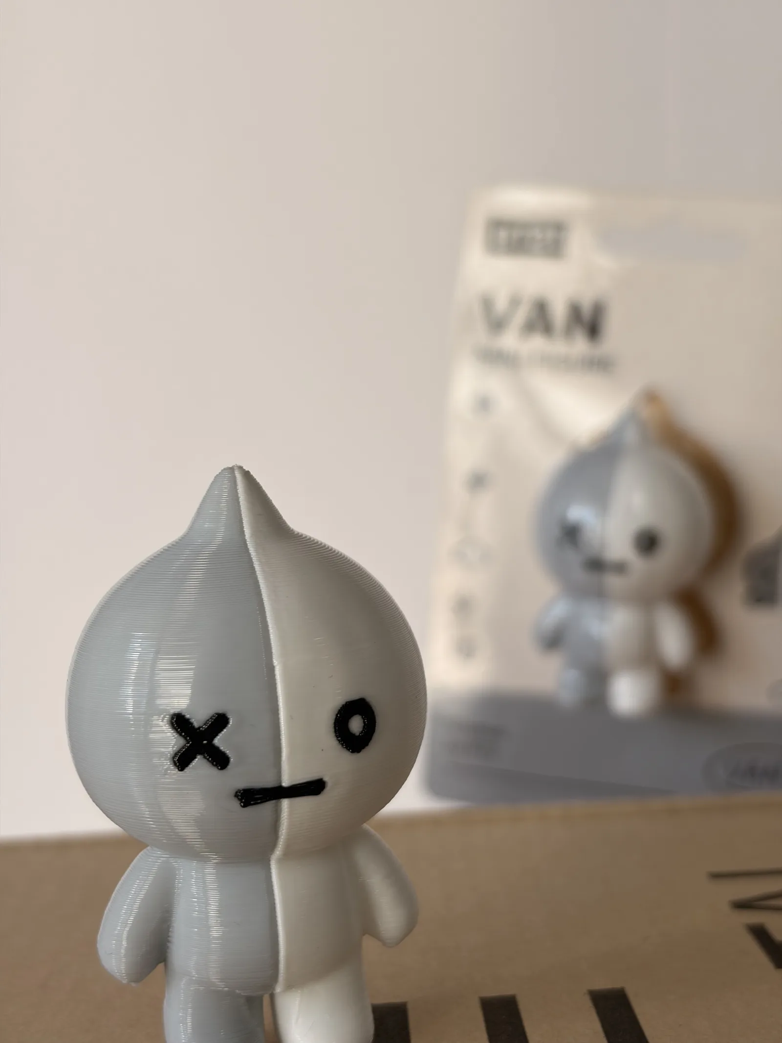 Mini figura de Van impresa en 3D junto a su blíster